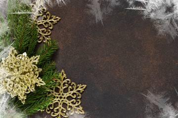 Christmas tree and decorative snowflakes, bells, ribbons on a brown background with space under the text.