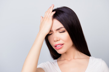 Fototapeta premium Close up portrait of confident entrepreneur having a headache, she has eyes closed and she is touching her forehead while standing over grey background. Stress and health care concept