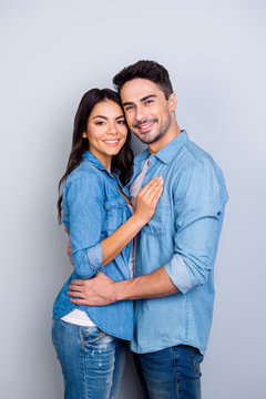 Together forever! Vertical photo of happy newlyweds dressed in jeans casual clothes, they are smiling, hugging and isolated on grey background