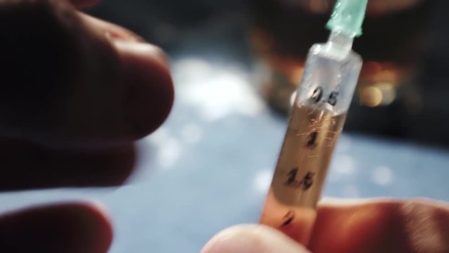 Drug addiction, Junkie tapping syringe full of heroin
