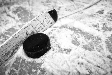 Close up of a hockey stick blade and puck on a snowy ice surface