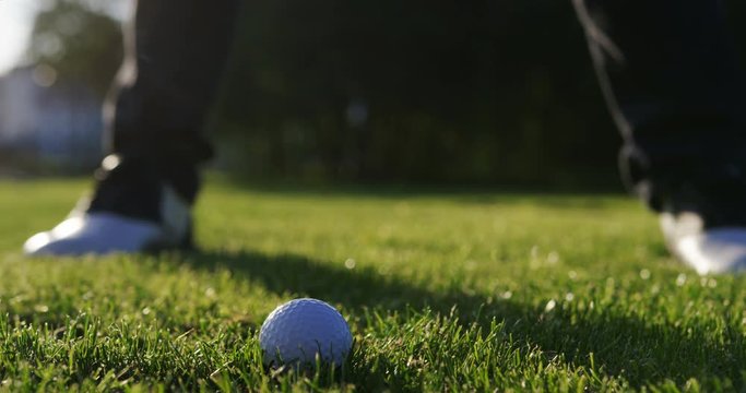 Close up of a ball being hitted by a golf club on the green golf pitch on a sunny summer day. Outside. slow motion