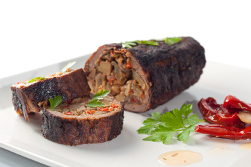 Stuffed meat with parsley and sun-dried tomatoes in olive oil on a white plate