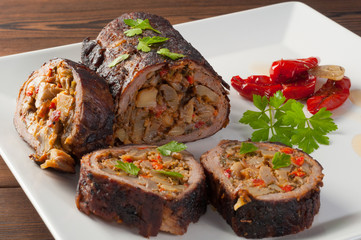 Stuffed meat with parsley and sun-dried tomatoes in olive oil on a white plate