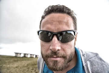 Macho with unshaven face, beard and mustache in black sunglasses