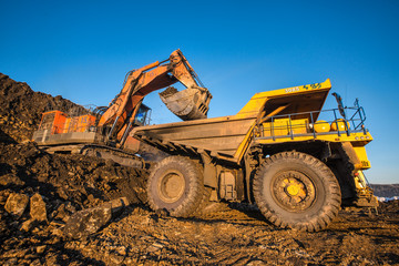 type of coal mine with working excavators and large cars

