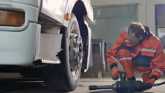 Mechanic preparing to unscrew the tire with screwdriver