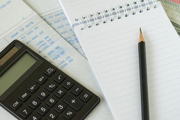 Financial salary man concept as pencil on white notebook with carbon salary slips and black calculator