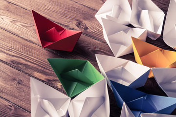 Business leadership concept with white and color paper boats on 