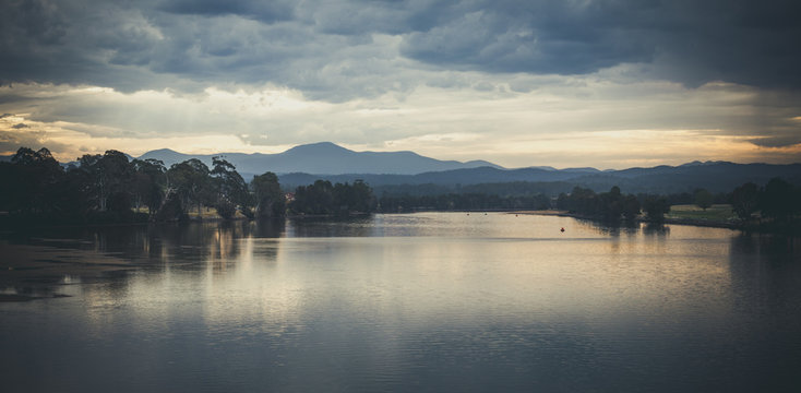 Landscape with shallow lake water and mountains at dusk. Image has analog look