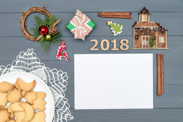Plate with tasty Christmas cookies with numbers 2018 and new year ornament on wooden table