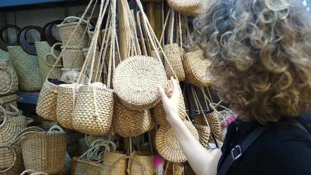 Young Woman Shopping And Choosing Trendy Wicker Bag On Market. 4K. 