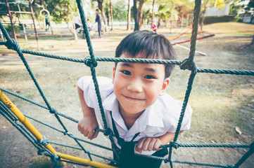 Asian child climbing in a rope at children playground. Vintage tone.