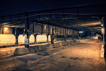 Dark Chicago city alley industrial train bridge underpass at night.