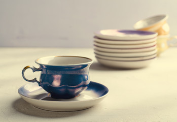 Obraz na płótnie Canvas Empty colorful porcelain tableware. Blue cup with plate on lilac background