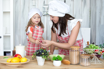 Mother and daughter cook dinner together in the kitchen. Portrait, childhood, family values.