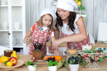 Mother and daughter cook dinner together in the kitchen. Portrait, childhood, family values.