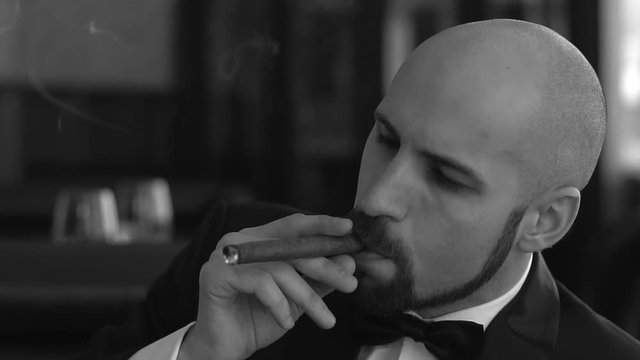Black and white image of a brutal man with a cigar. Close-up. Slow motion.
