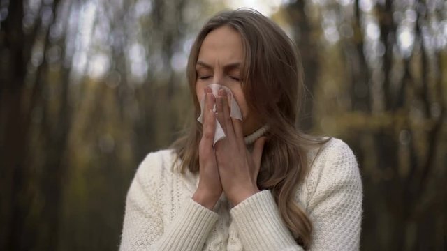 Lady sneezing and blowing her nose into napkin, seasonal allergies, epidemic