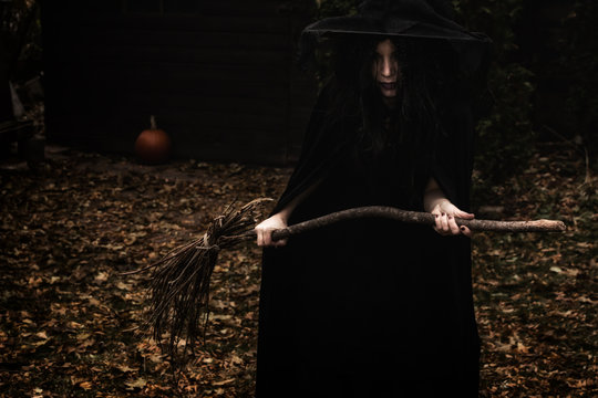 Wicked Looking Witch Holding A Broom In A Rural Autumn Scene.