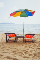 beach in Thailand, two deck chairs and colorful umbrella near the sea