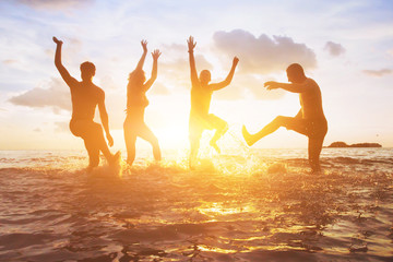 crowd of friends having fun in the water at sunset, silhouettes of happy people enjoying summer...