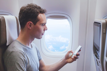 passenger using mobile phone smartphone in the airplane, wifi connection in plane during flight