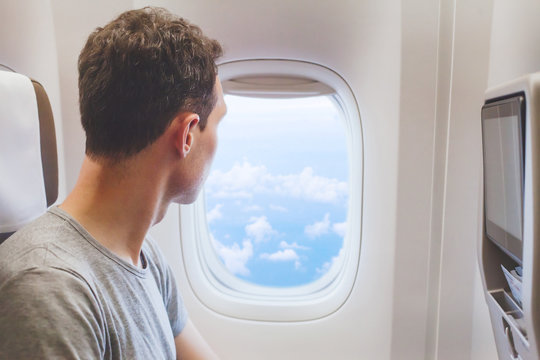passenger traveler looking at window in airplane, travel by flight, man tourist sitting in air plane