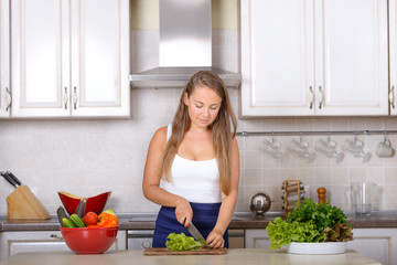 Woman cutting a salad in kitchen