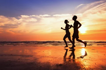 Wall murals Jogging running background, sport and workout, silhouettes of people jogging at sunset beach
