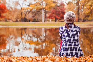 autumn cozy background, beautiful woman sitting near the lake in fall season