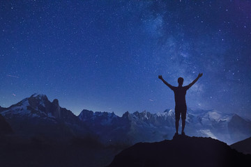 person looking at night starry sky , silhouette of man standing with raised hands dreaming about...