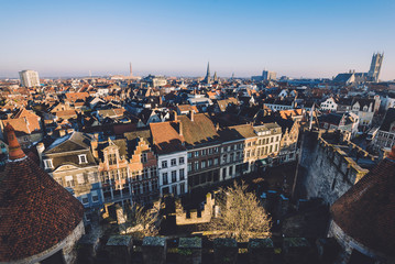 Fototapeta na wymiar Ghent, Flanders, Belgium - December 30th, 2016. Gent Old town panoramic view from above Gravensteen castle. Ghent skyline with merchant houses roofs, St. Bavo and St.Jacob's cathedrals by golden hour.