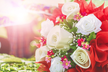 a bouquet of white and red roses with small pink flowers, in front of a bright, blurry background.