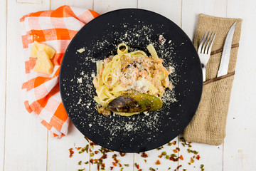 Seafood Pasta with mussels and basil in white plate on wooden table.
