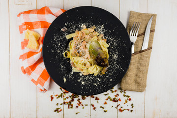 Seafood Pasta with mussels and basil in white plate on wooden table.