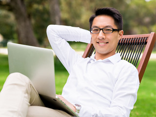 Young businessman using laptop while sitting outdoors