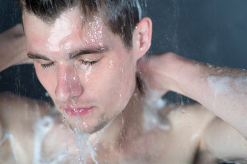 Young man in shower with black background