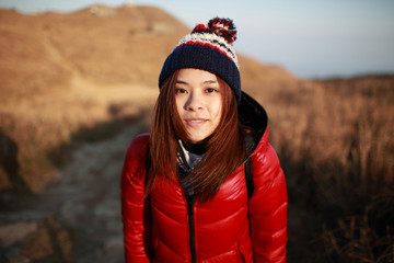 Beautiful sweet Young girl wear the down jacket and hat  Travel in winter view under sunset evening on the mountain landscape countryside background, face close up