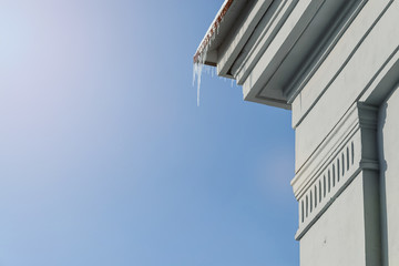Icicles hanging from the corner of the building on a cloudless day