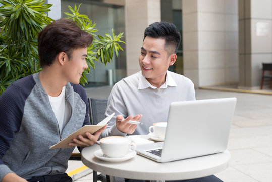 Handsome Asian business colleagues or college students work together using laptop, startup project meeting or teamwork brainstorm concept, at coffee shop or modern office