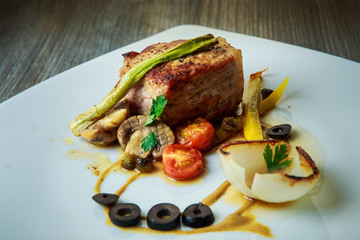 roasted meat decorated with grilled tomato, mushrooms, yellow pepper, green onion and black olive