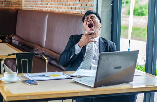 Tired man yawning at workplace in coffee shop