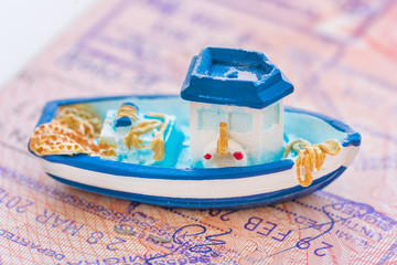 Small blue toy boat lying on the passport page with visa stamps