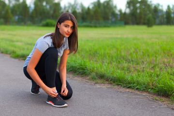 A teenage girl ties her shoelaces, prepares for a run
