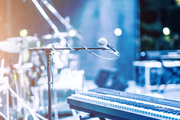Microphone and synthesizer on concert stage with defused bokeh lights blue colour background