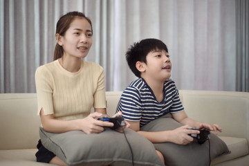 Asian woman with asian boy playing video games at home