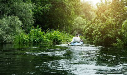People canoeing on the river surrounded by dense green forest