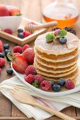 Mixed berry pancake with honey on wooden table