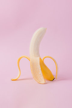Peeled banana on pink background with copy space